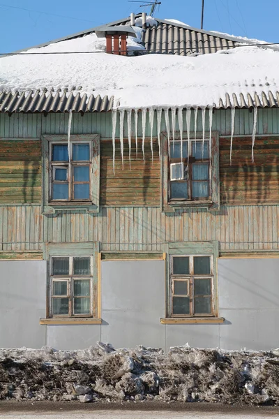 Stock image Icicles on the roof of an old wooden house.