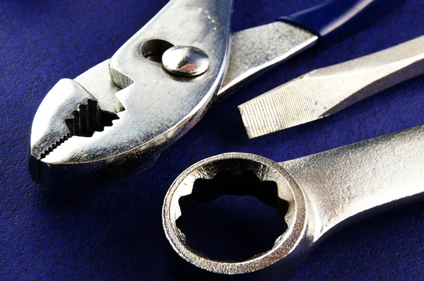 Chave de fenda, chave de fenda e alicate close-up no fundo texturizado azul — Fotografia de Stock