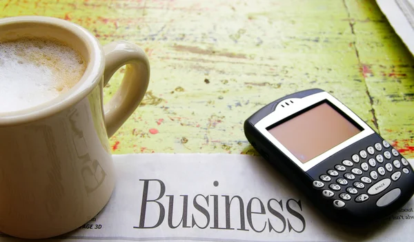 Kopje koffie, mobiele telefoon en krant bedrijf sectie — Stockfoto