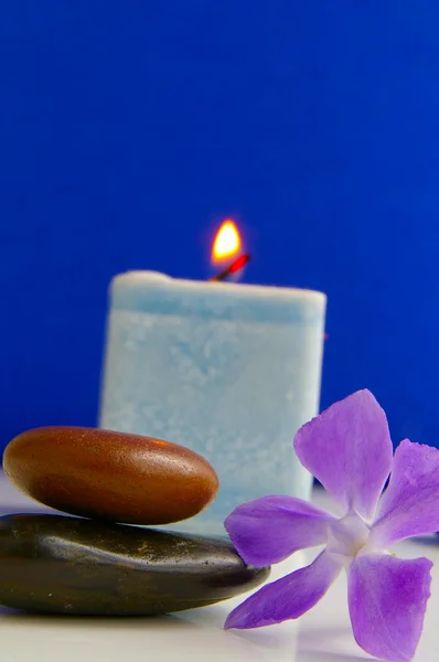 Pedras lisas empilhadas com pequena flor e vela — Fotografia de Stock