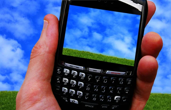 Hombre sosteniendo un teléfono celular, con la imagen del cielo azul , —  Fotos de Stock