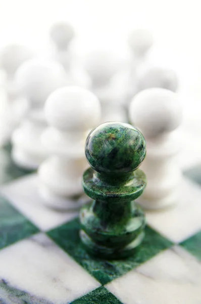 Skupina šachy figurkami na šachovnici, jedna v čele — Stock fotografie