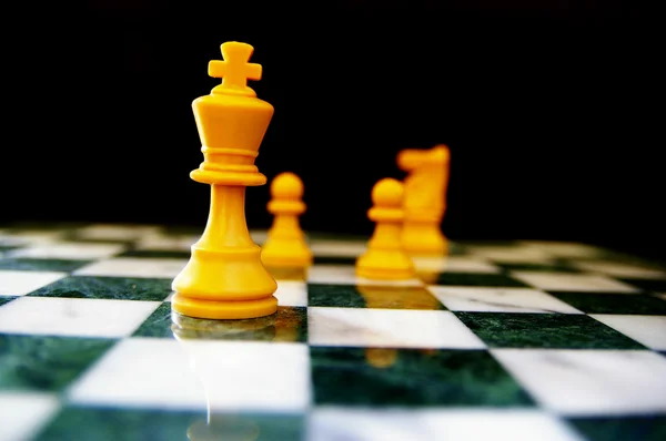 Skupina šachy figurkami na šachovnici, jedna v čele — Stock fotografie