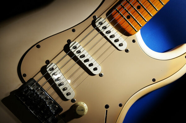 Closeup of an electric guitar, on blue