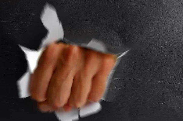 Man's hand in a fist punching thru a hole — Stock Photo, Image