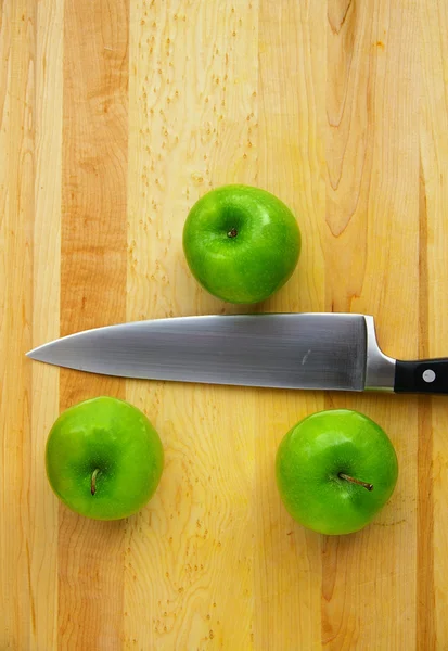 Tres manzanas en una tabla de cortar, con un cuchillo —  Fotos de Stock