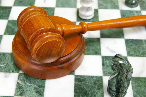 Legal gavel on a chess board with game pieces — Stock Photo, Image