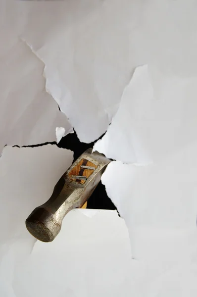 Martelo perfurando papel thru criando um buraco rasgado — Fotografia de Stock
