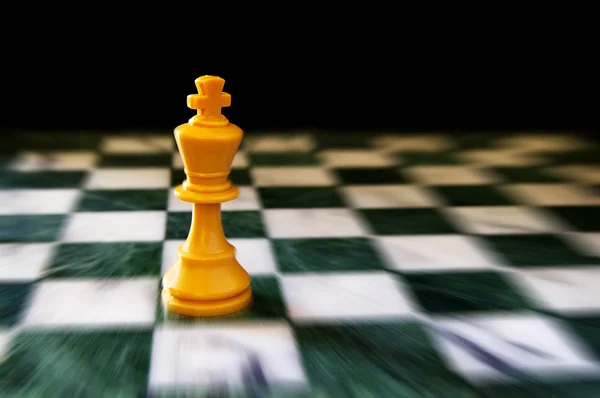 Koning op een schaakbord, tegen zwarte achtergrond — Stockfoto