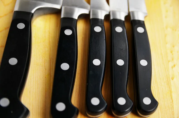 stock image Array of kitchen knives on a wooden cutting board