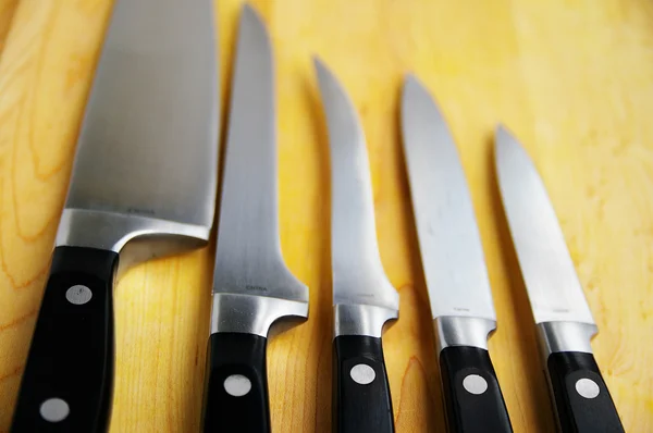 stock image Array of kitchen knives on a wooden cutting board