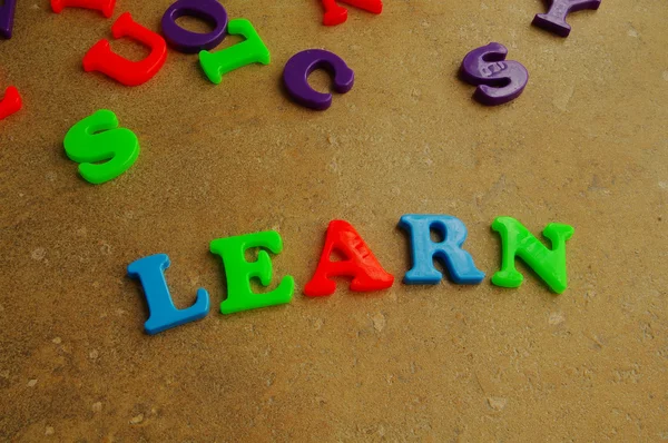 Children's colorful plastic letters spelling out "learn" — Stock Photo, Image