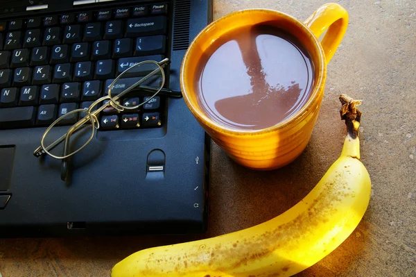 Cup of morning coffee with laptop and a banana — Stock Photo, Image