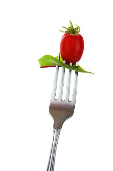 stock image Cherry tomato and spinach leaf on a fork, over white