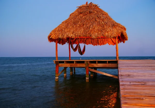 Dock with tropical thatched roof palapa at dusk — Stock Photo, Image