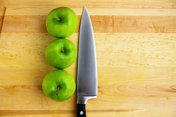 Tres manzanas en una tabla de cortar, con cuchillo afilado —  Fotos de Stock