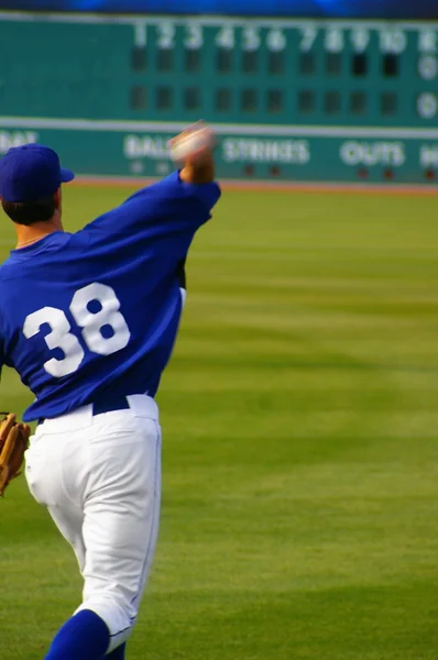 Giocatore di baseball lanciare la palla, con tabellone segnapunti sullo sfondo — Foto Stock