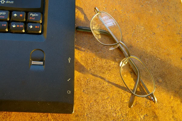 Laptop és a szemüveg a meleg reggeli fényben — Stock Fotó