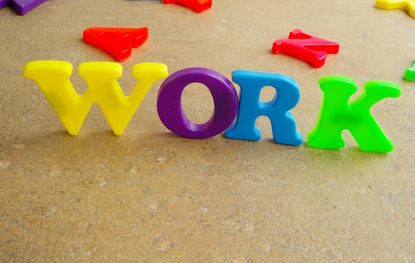 Letras plásticas coloridas das crianças soletrando "trabalho " — Fotografia de Stock