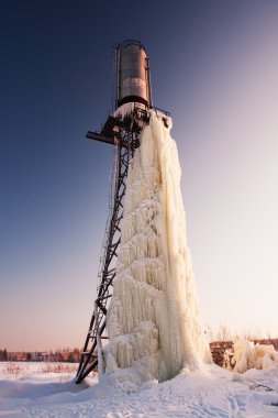 Big icicle hanging from water tower in winter. clipart