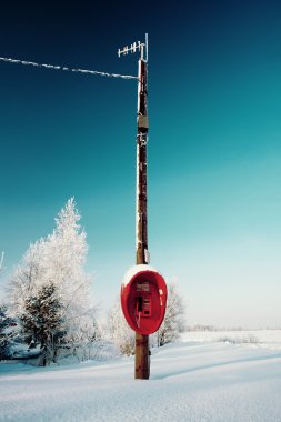 Not used red phone hanging on a pole in winter field clipart