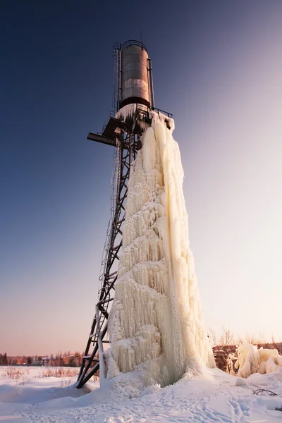 Grande ghiacciolo appeso alla torre d'acqua in inverno . — Foto Stock
