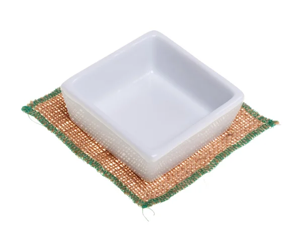 Plato cuadrado blanco en una servilleta de arpillera, aislado en un blanco —  Fotos de Stock