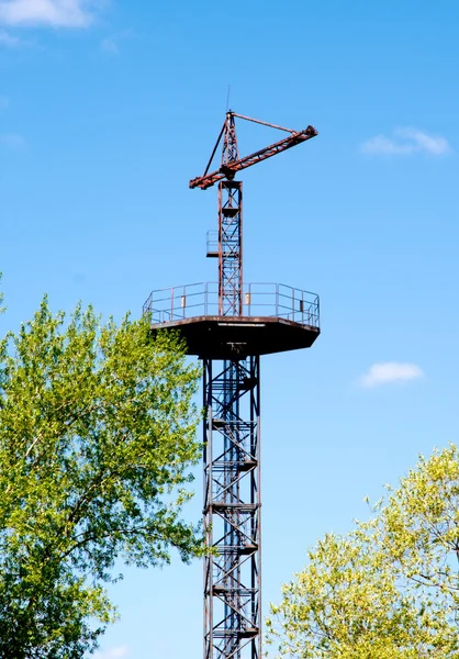 Gamla tornet med en kran på en bakgrund av blå himmel. — Stockfoto