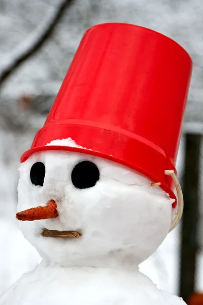 Un muñeco de nieve con un cubo rojo en la cabeza . — Foto de Stock