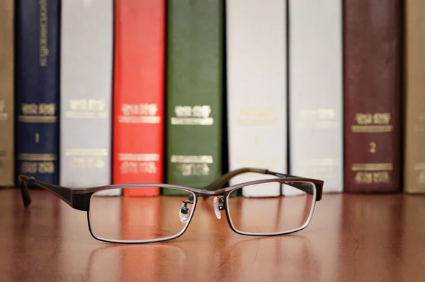 Bril op de boekenplank — Stockfoto