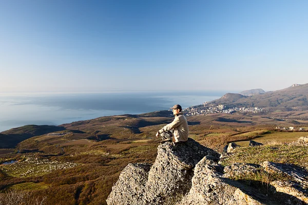 Young man sitting on the rock — Stock Photo, Image
