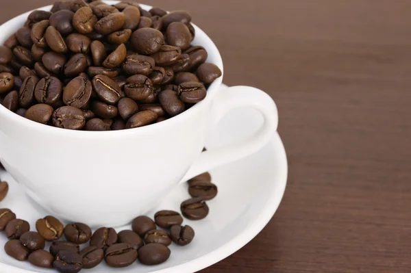 Xícara de grãos de café em uma mesa — Fotografia de Stock