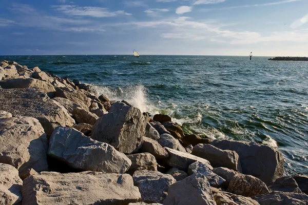 Rocky beach with yacht on the horizon — Stock Photo, Image