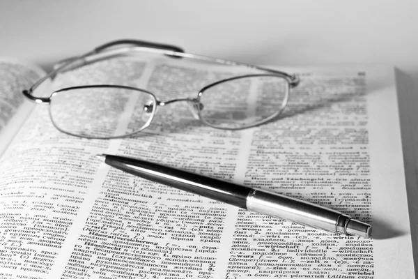 Dictionnaire avec une paire de lunettes et stylo — Photo