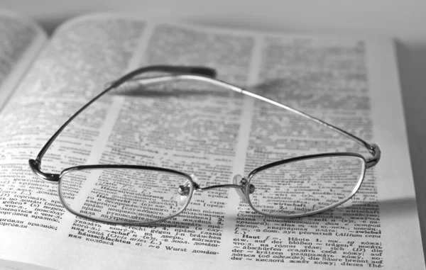 Monochromes Bild einer Brille auf einem offenen Buch — Stockfoto