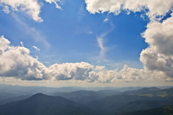 Блакитне хмарне небо над горами — стокове фото