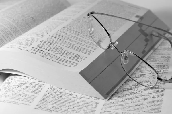 Monochromes Foto aufgeschlagener Bücher mit Brille — Stockfoto