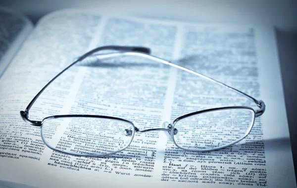 Aufgeschlagenes Buch mit Brille darauf — Stockfoto