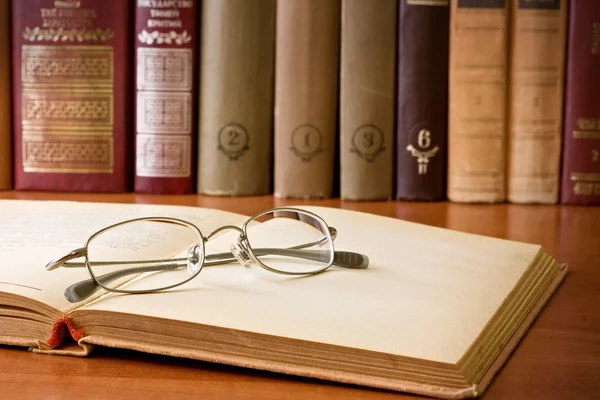 Vintage book and glasses in library — Stock Photo, Image