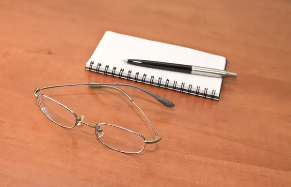Блокнот с очками и ручкой — стоковое фото