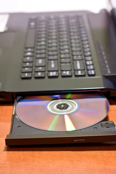 Immagine ravvicinata di un computer portatile e di un disco CD / DVD — Foto Stock