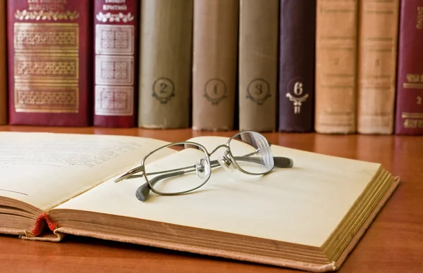 Book and glasses in library — Stock Photo, Image