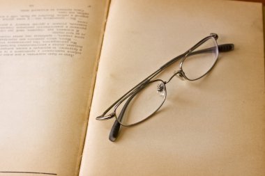 Old book with reading glasses clipart