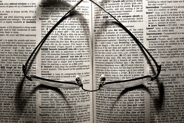 Glasses lying on a dictionary — Stock Photo, Image