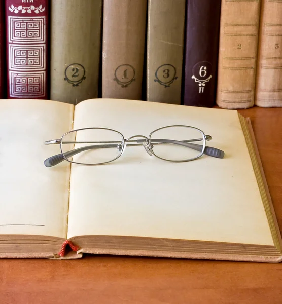 Glasögon om över en öppnade gammal bok — Stockfoto
