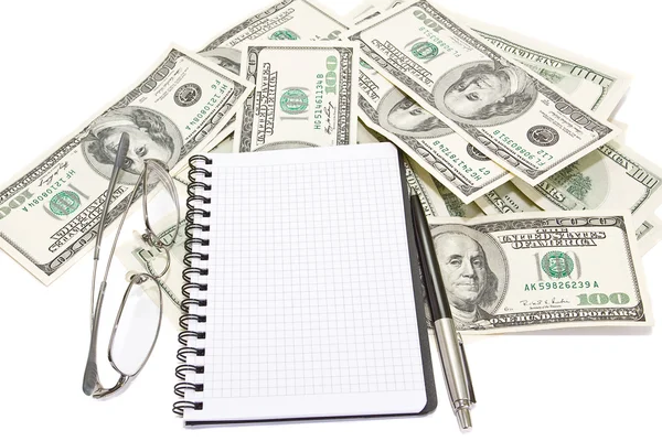 Pen, Kladblok en bril op geld achtergrond — Stockfoto