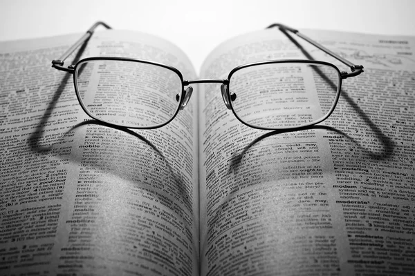 Aufgeschlagenes Buch mit Brille im Dunkeln — Stockfoto