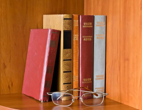 Livros retrô e óculos na estante — Fotografia de Stock