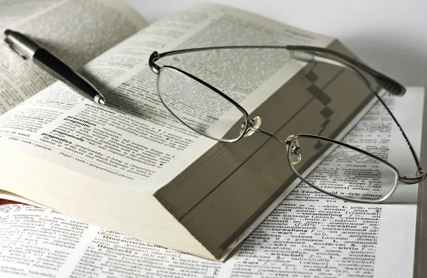 Açık kitap, gözlük ve kalem — Stok fotoğraf