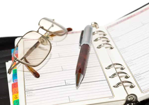 Pen and eyeglasses on agenda page — Stock Photo, Image